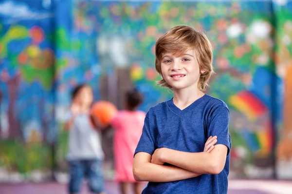 Confident caucasian young boy at school following classmates pla — Stock Photo, Image