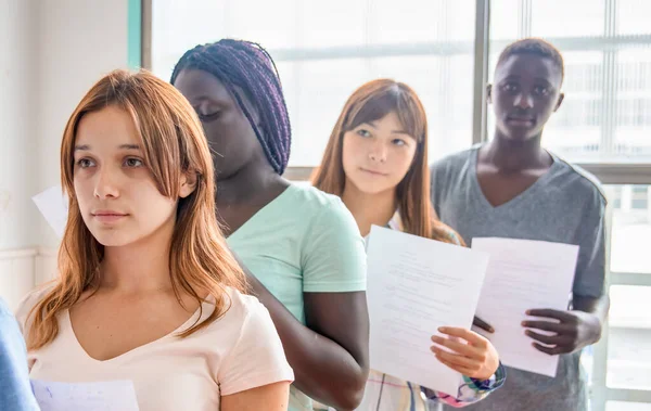 Grupo Adolescentes Multiétnicos Que Entregan Prueba Escolar —  Fotos de Stock