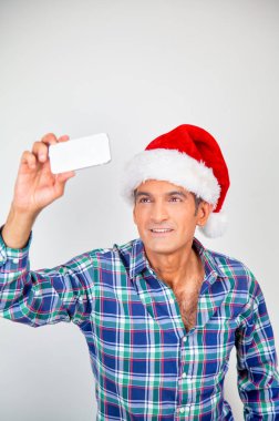 Evde Noel şapkalı mutlu bir adam izole edilmiş selfie çekiyor.