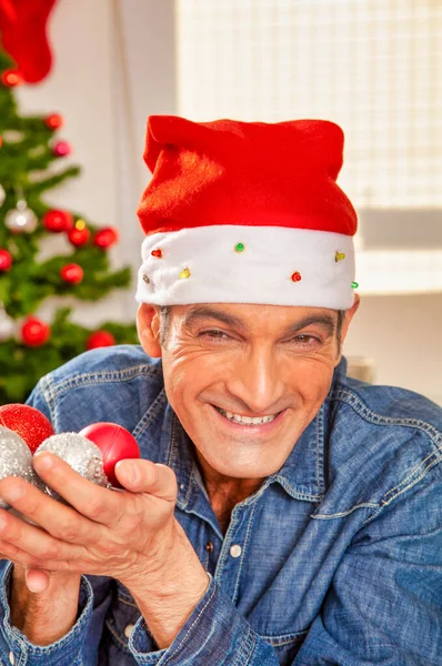 Homem com chapéu de Natal vermelho segurando bolas de árvore — Fotografia de Stock