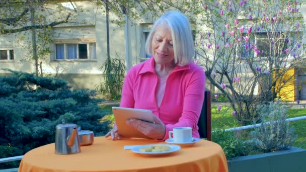 Frau in den Siebzigern telefoniert im Freien mit Tablet — Stockvideo