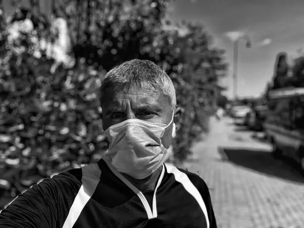 Male athlete running outdoor in the park wearing mouth mask.