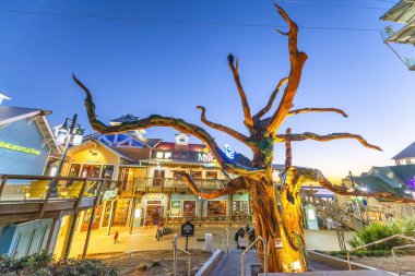 DESTIN, FLORIDA - ŞUBAT 2016: Dükkanlar ve turistlerle gün batımında Destin Limanı Boardwalk.