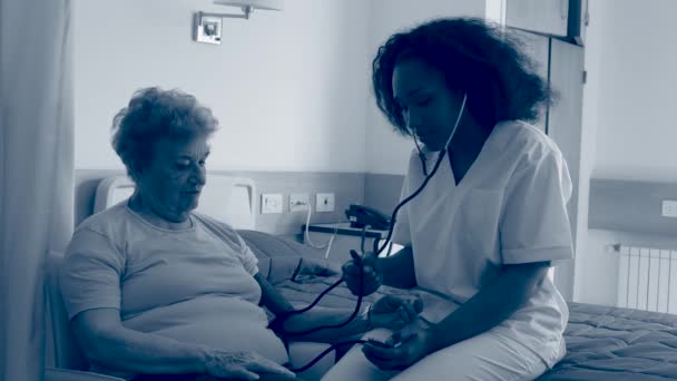 Медсестра измеряет артериальное давление пожилой женщине в больнице. Сепия тонизированная — стоковое видео
