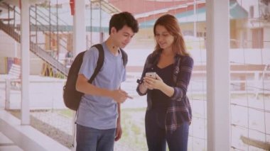 Okul koridorundaki akıllı telefondan fikir alışverişinde bulunan birkaç beyaz ergen, klasik filtre.