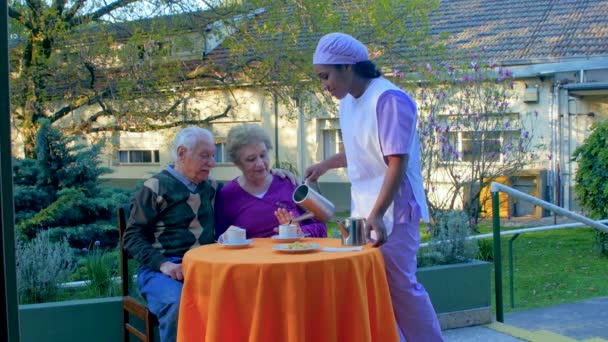 Älteres Ehepaar frühstückt im Garten mit Hilfe einer Krankenschwester — Stockvideo