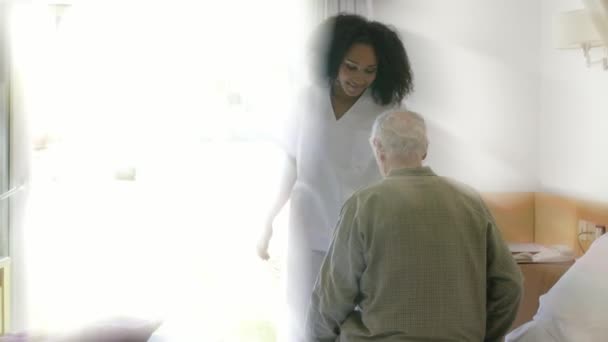 Junge afrikanische Krankenschwester hilft einem älteren Mann beim Schlafengehen im Krankenhauszimmer. Lichtstrahlen von hinten — Stockvideo