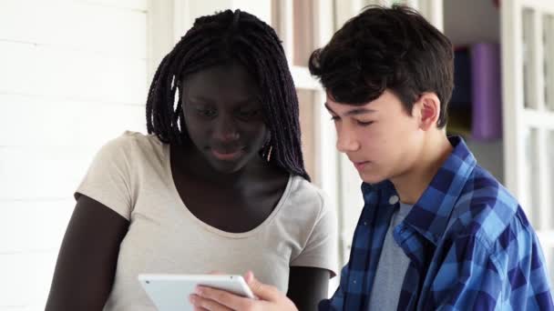 Movimiento lento de adolescentes africanos y caucásicos usando tableta en el pasillo de la escuela — Vídeos de Stock