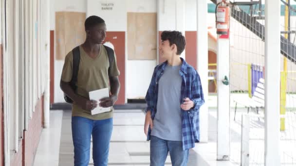 Movimento lento de adolescentes africanos e caucasianos conversando no corredor da escola — Vídeo de Stock