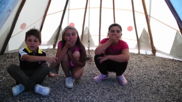 Trójka dzieci bawi się indiańskimi dźwiękami ustami i rękami, zwolnione tempo — Wideo stockowe