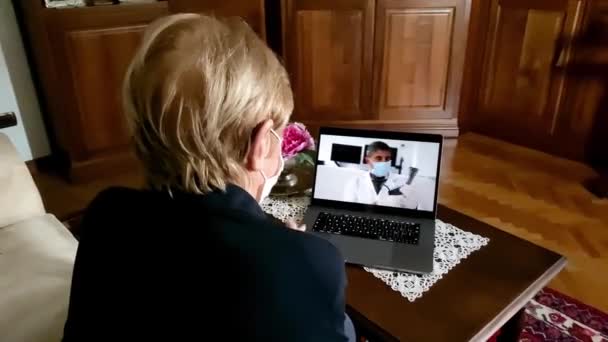 Donna anziana a casa stancare maschera in tempi coronavirus su un videocall con il suo medico — Video Stock