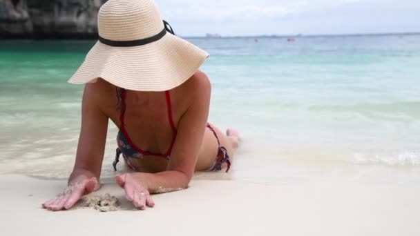 Bella donna in vacanza rilassante sdraiata sulla spiaggia indossando cappello di paglia. Vacanza e concetto di viaggio — Video Stock