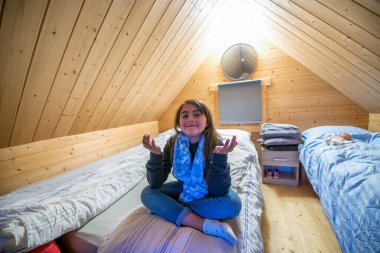 Tahta bir yatak odasında, Yoga pozisyonunda sevimli genç bir kız..