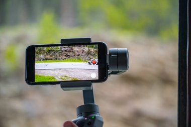 Dengeleyicili akıllı telefon bir dağ yolunun videosunu çekiyor.