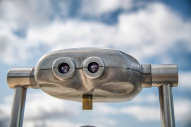 Arka planda mavi gökyüzü olan metal dürbünler. Turizm konsepti.