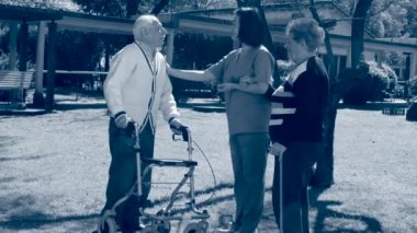 Genç hemşirenin yardımıyla bahçede gazete okuyan yaşlı çift. Sepya tonlandırılmış