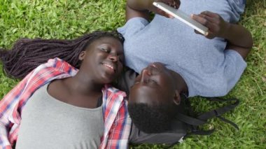 Bir parkta oturmuş tabletle çalışan iki Afrikalı genç. Yavaş çekim