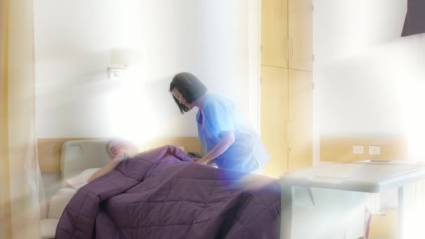Молодая азиатская женщина-врач помогает пожилому мужчине встать с больничной койки. Световые лучи сзади — стоковое видео