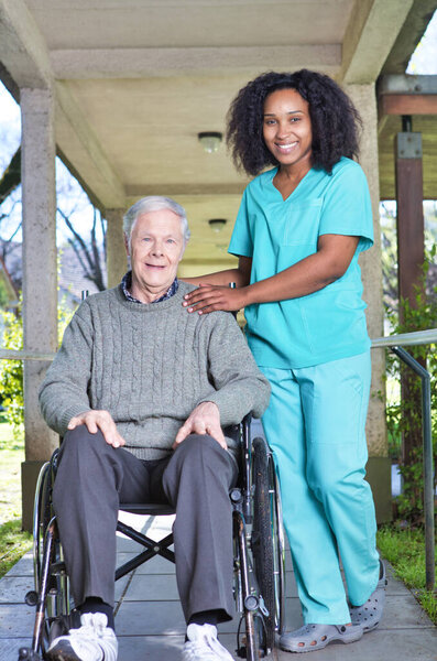 African nurse assisting elderly man on the wheelchair.