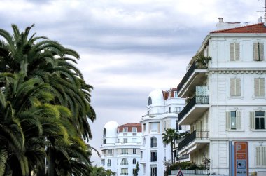 Bulutlu bir günde Fransa 'da Cannes binaları ve palmiyeleri.
