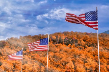 New England 'da Amerikan bayrakları sallıyor, sonbahar yeşillik mevsimi turuncu renkler ve mavi gökyüzü.