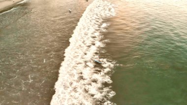 Gün batımında kıyı şeridi boyunca dalgaların havadan görünüşü.