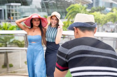 Asyalı bir adam iki Asyalı kadının fotoğrafını çekiyor. Seyahat ve tatil konsepti.