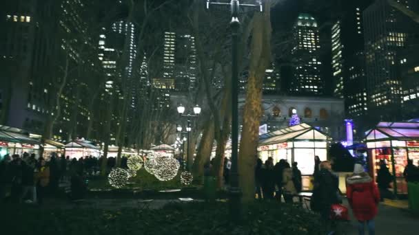 2017 년 12 월 7 일에 확인 함 . NEW YORK CITY, USA - DECEMBER 7, 2018: Bryant Park market at night with tourists, Manhattan, New York City, USA, slow motion — 비디오