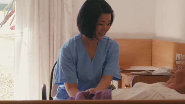 Медленное движение азиатской женщины-врача, помогающей пожилым пациентам мужского пола на больничной койке. Концепция счастья, реабилитации и ухода на пенсию — стоковое видео