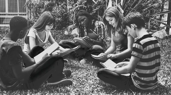 Счастливая Группа Подростков Смешанных Рас Сидящих Траве Делая Школьный Урок — стоковое фото