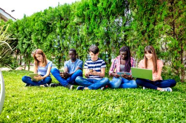 Çimlerin üzerinde oturmuş okul dersi veren bir grup melez genç. Okul konseptine dönelim..