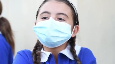 Salgından sonra okulun ilk günü. Yüz maskesi takan genç kız.