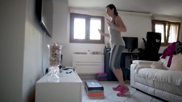 Mujer haciendo ejercicio de gimnasio paso en casa en el tiempo coronavirus — Vídeo de stock