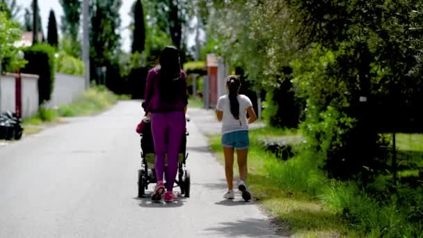 Vrouw assistente moeder in de rolstoel loopt door een straat met haar dochter. Drie generaties mensen — Stockvideo