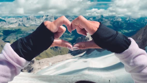 Mulher criando sinal de coração com as mãos em um cenário de montanha — Vídeo de Stock