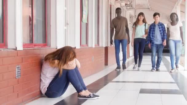 Грустный азиатский подросток сидел в школьном коридоре и думал о своих проблемах. Группа подростков встала у нее на пути — стоковое видео