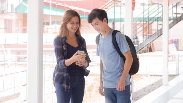 Два подростка смотрят на смартфон в школьном коридоре — стоковое видео
