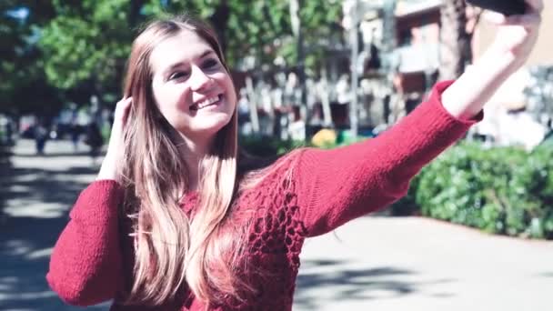 Chica joven tomando selfies en el parque de la ciudad. Imágenes en cámara lenta — Vídeo de stock