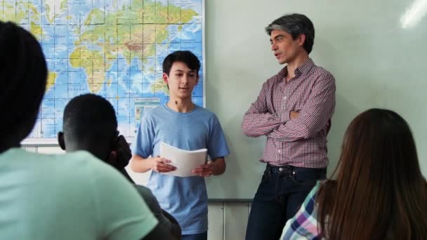 Professor entrevistando menino em uma sala de aula adolescente multiétnica. Movimento lento — Vídeo de Stock