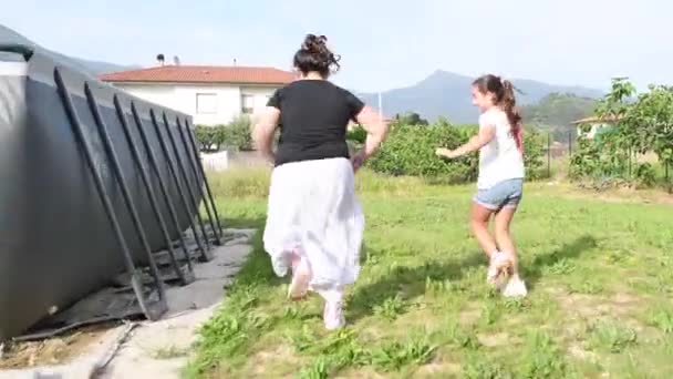 Twee jonge meisjes genieten van outdoor tijd, hardlopen op het gras, achteraanzicht — Stockvideo