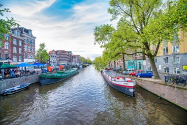 AMSTERDAM, NETHERLANDS - 25 NİSAN 2015: Kanalda tekneli geleneksel evler ve binalar.
