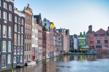 Amsterdam 'ın şehir kanalları boyunca uzanan klasik binaları güneşli bir öğleden sonra, Hollanda.
