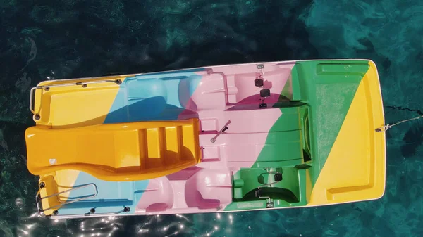Colourful Pedal Boat on the shoreline. Overhead aerial view from drone. Slow motion