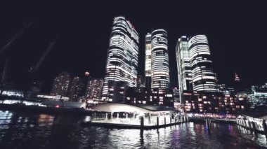 Hareket halindeki bir tekneden Barangaroo Gökdelenleri 'nin gece görüşü, Sydney. Yavaş çekim