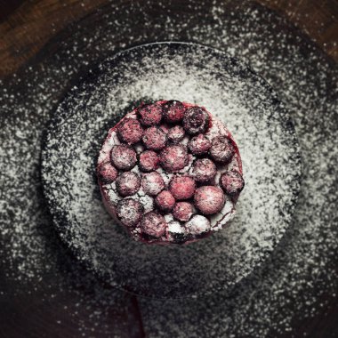 Tüm kiraz ile dekore edilmiş ve koyu arka plan üzerine pudra şekeri serpilir kiraz kek üstten görünüm