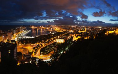 Malaga şehrinin manzarası, Ispanya. Gün batımı gökyüzü ile gece ışıklandırılmış binalar ile Belediye Binası ve liman havadan görünümü