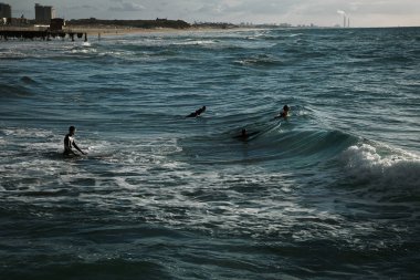 Okyanusta sörfçüler gün batımı içinde daraltır