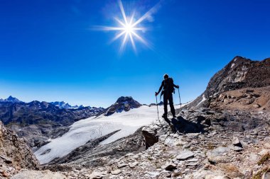 Fiyatı yüksek dağ geçidi, İtalyan Alpleri, Val D'Aosta, İtalya ulaşır. İçinde tepeler Gran Paradiso Milli Park arka plan. Yetişkin erkek beyaz modeli; Güneşli yaz günü. Konsept: macera, başarı, mutluluk, dayanıklılık.