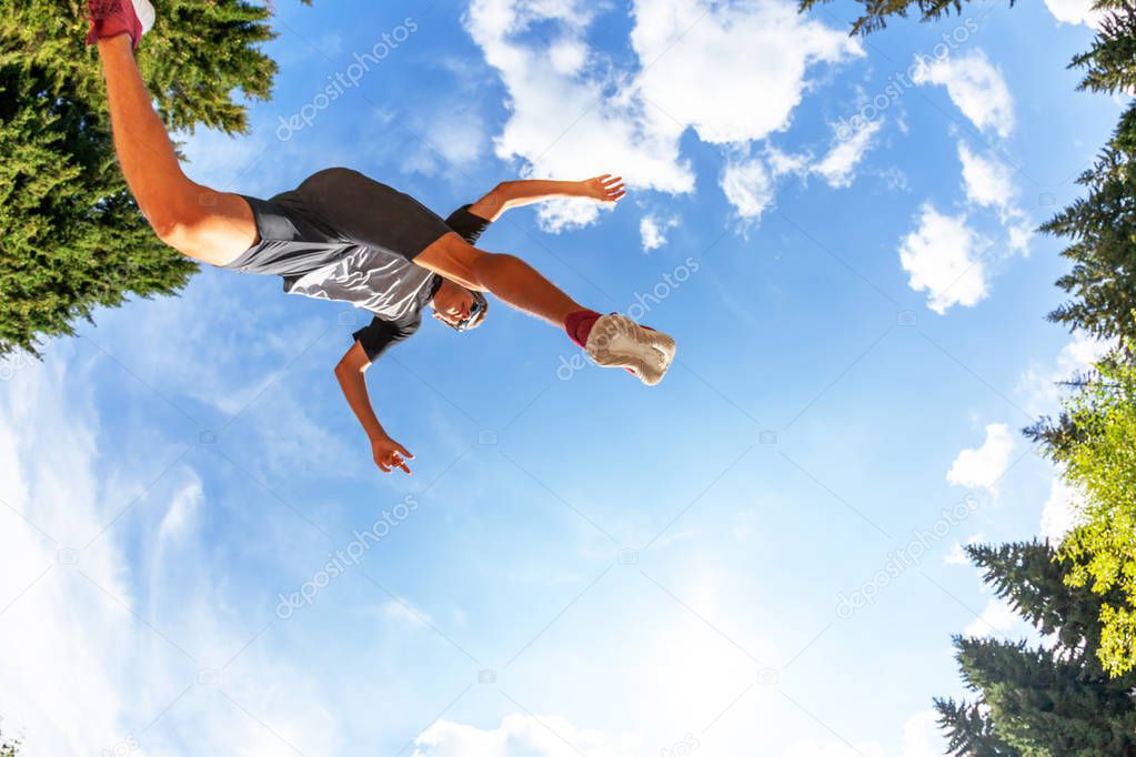 young man jumping on mountain meadow. View from Below. Daylight, summer season.