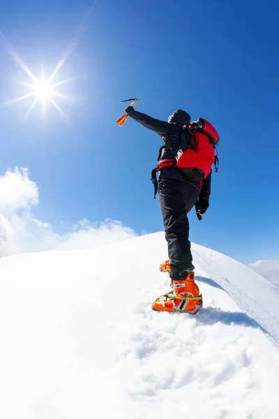 Наверху: одинокий альпинист достигает вершины снежной горы — стоковое фото